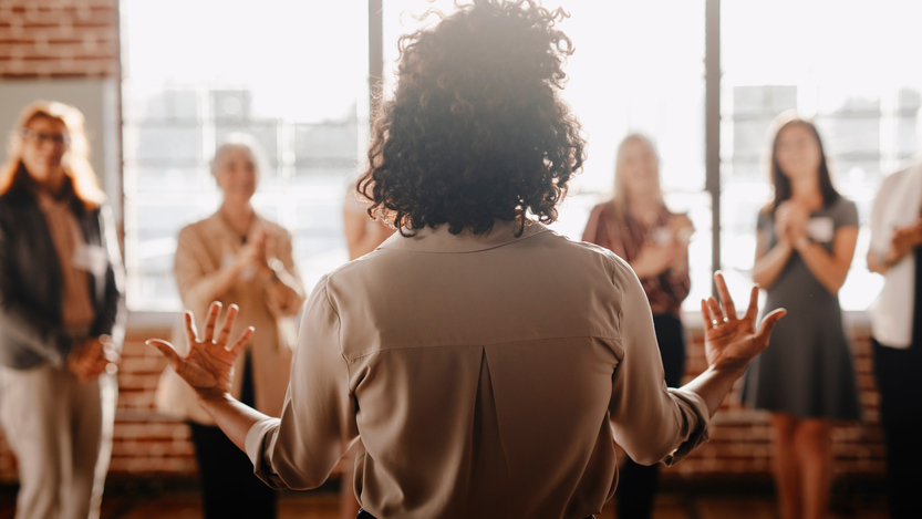 A leader faces four clapping team members.
