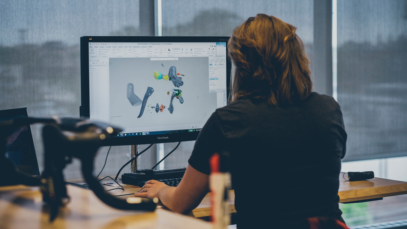 A person faces a computer while designing bicycle parts