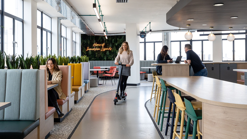 Person-on-scooter-by-colourful-booth-seating-and-chairs-in-Immersive-Labs-Bristol.jpg