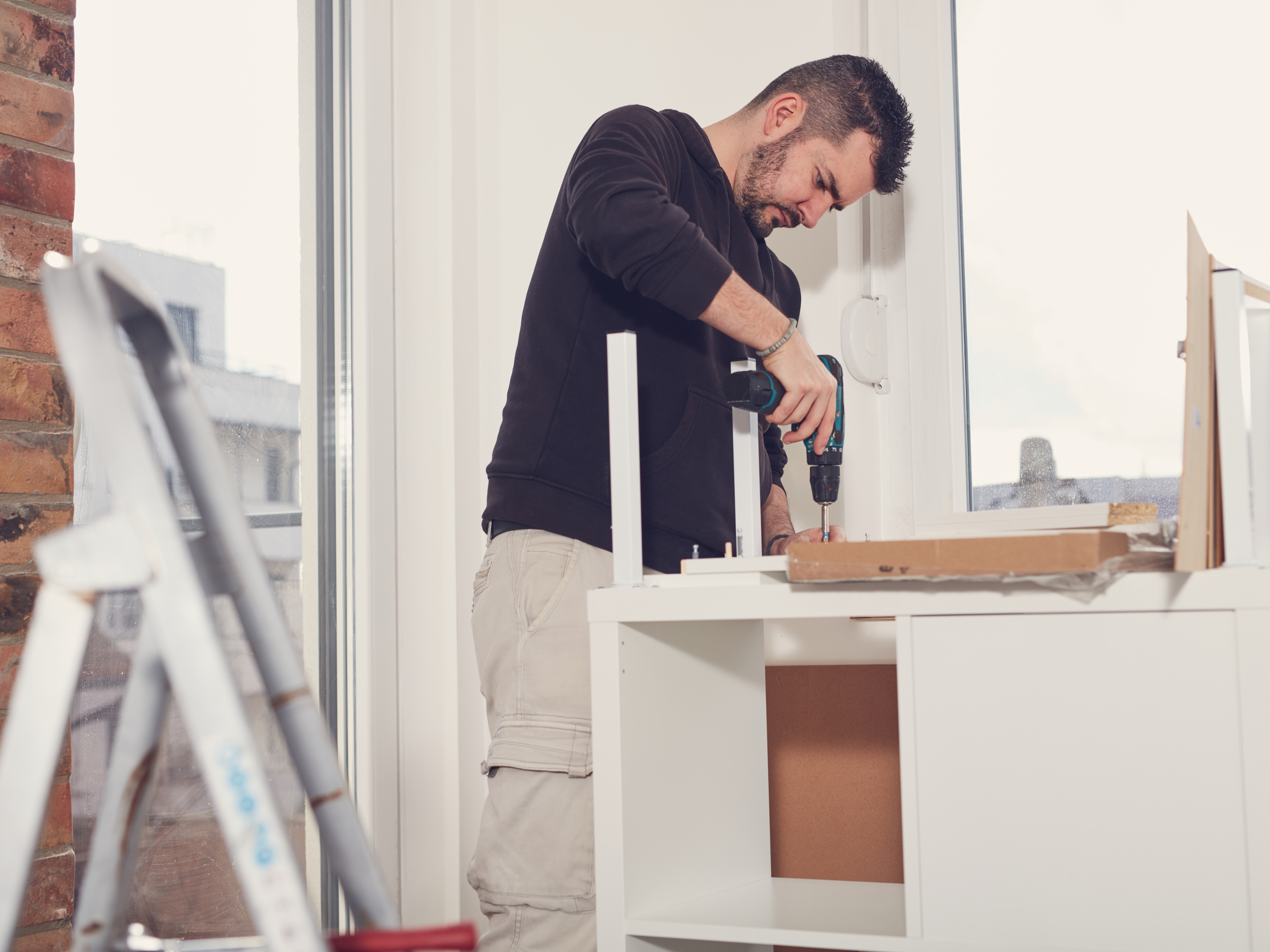 A handyman assembles furniture for people who have just moved into a new home