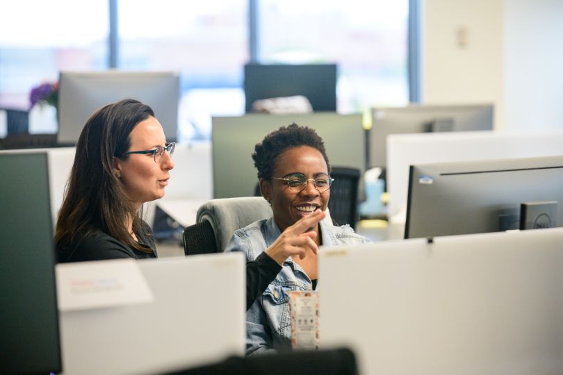 two women working above computers
