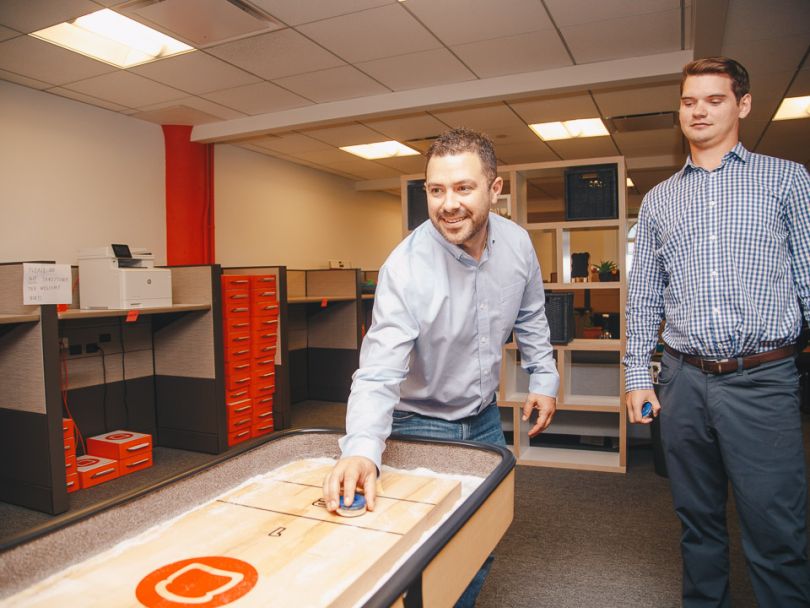 Adam Mavrikos plays shuffleboard inside Toast's office
