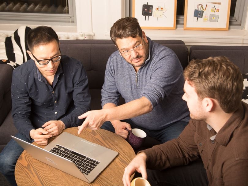 Mike Shaw shows computer screen to coworkers