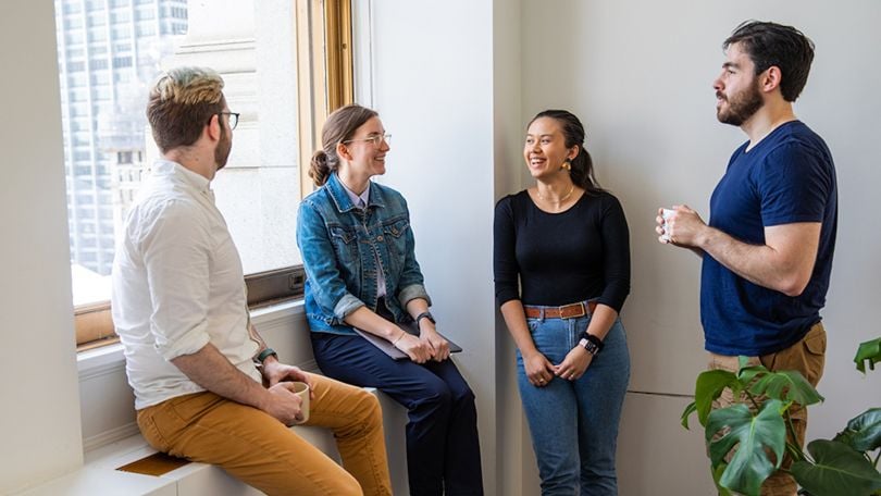 Orchard team members chat by a window. 