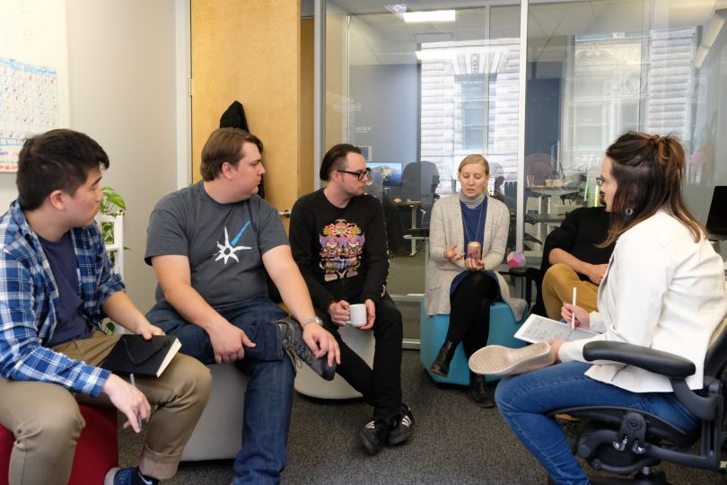 Team of workers sit together in casual meeting room
