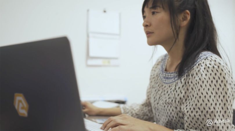 AMP Robotics team member sitting at a desk in the office working on a laptop