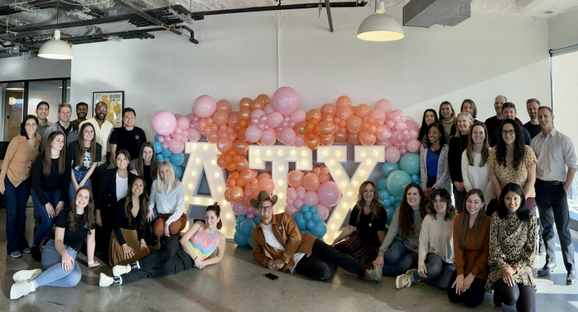 big employee group photo in front of huge lit-up ATX sign
