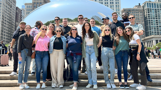 A group of 20 young employees dressed casually and posing in front of the famous Cloud Gate “bean” sculpture in Chicago’s Millennium Park.