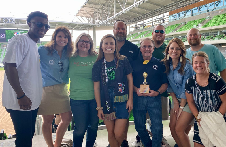 AffiniPay group photo at a sporting event with one team member holding a trophy