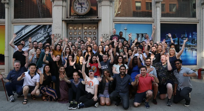 Animoto employees pose together in front of a colorful mural.