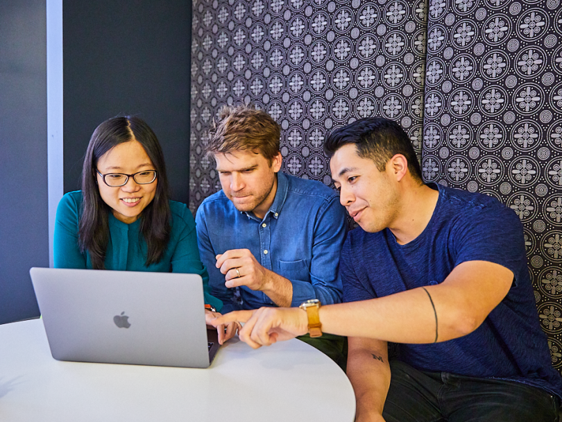Yi Fang Chen works at a table with coworkers