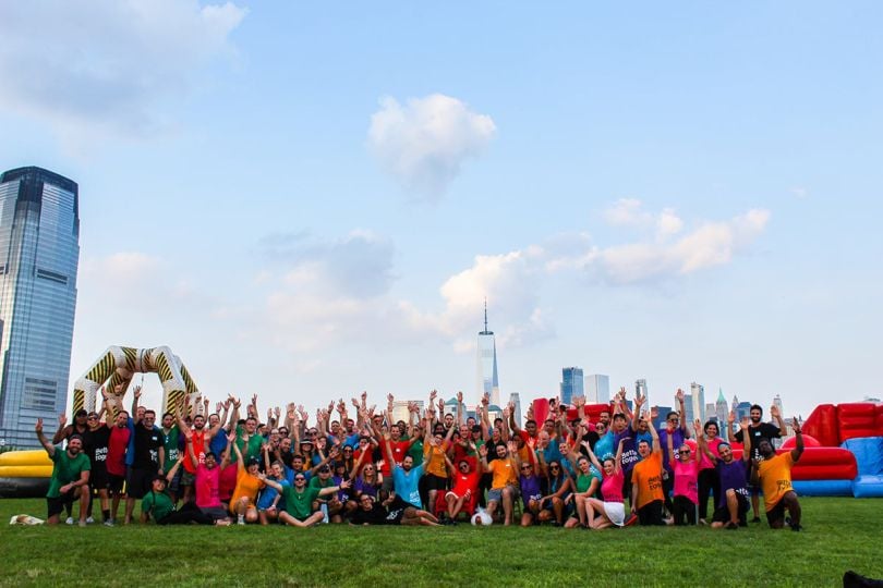 Bizzabo team members at an inflatable obstacle course with the New York skyline in the background