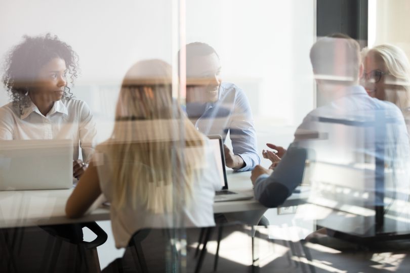 stylized image of a board room with people form diverse backgrounds sitting around a table