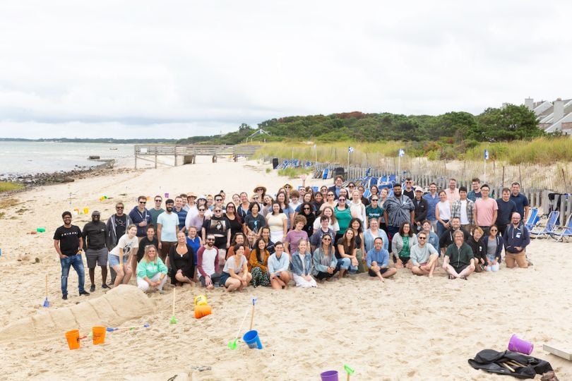 A large group of people smile on the beach