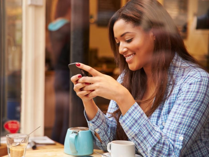 A woman in a cafe reads on her phone