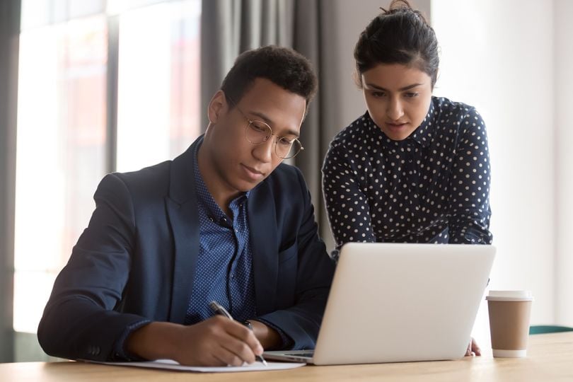 multi-ethnic colleagues working together affirming checking papers, using online business app