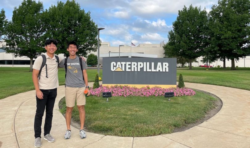 Two young men stand outside the Caterpillar office