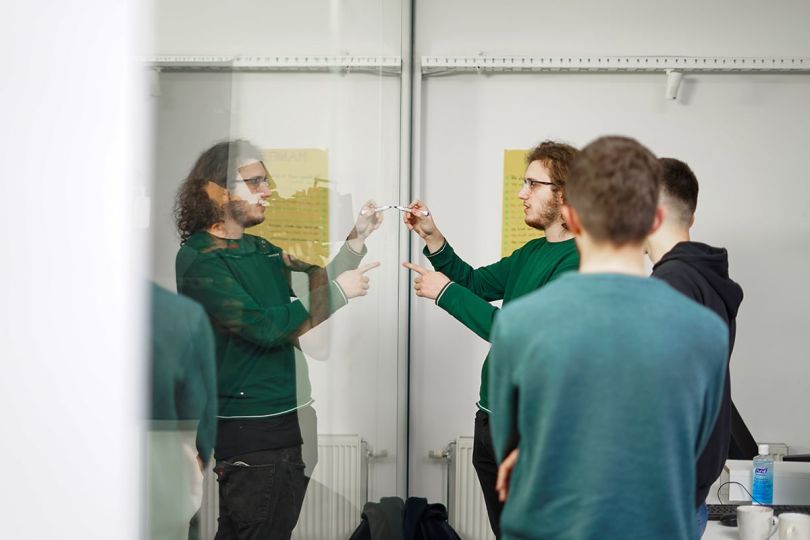 Celonis team member writing on a whiteboard with colleagues gathered around