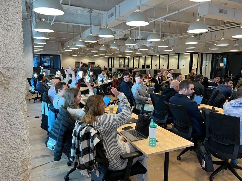 Celonis team members sit in classroom-style seating arrangement in a large room for training.