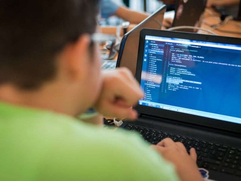 A person sitting in front of a laptop where code is being written