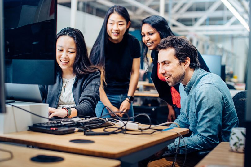 Covariant team members having a meeting gathered around a computer monitor