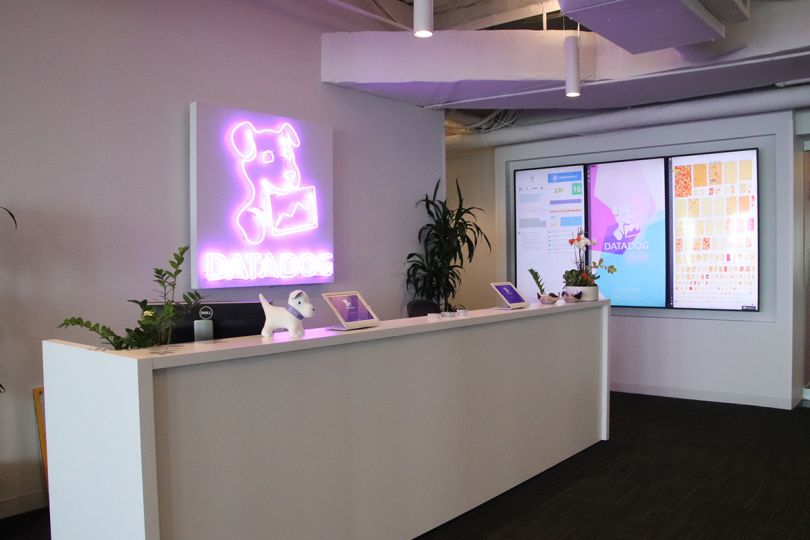 Datadog reception desk with a neon company logo on the wall