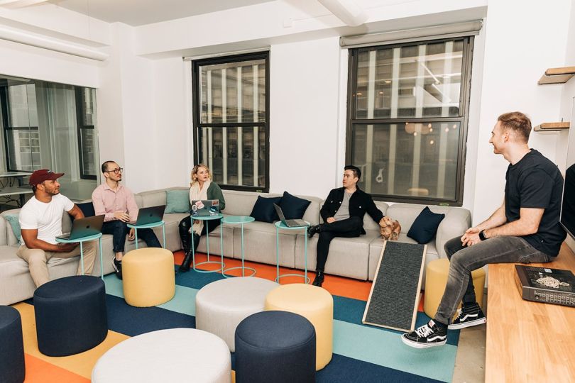 DearDoc coworkers sitting on a couch in the office having a team huddle