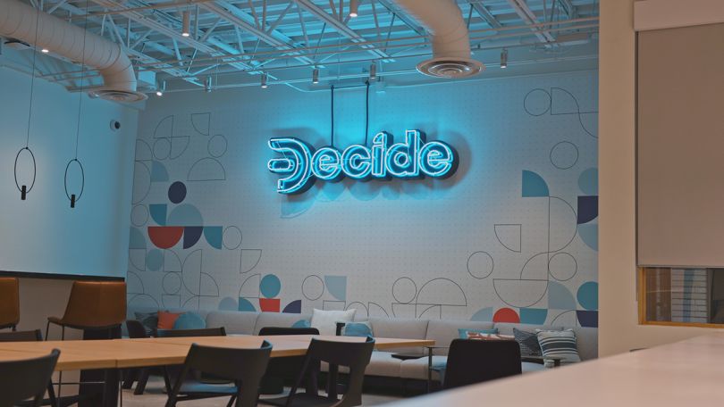 Neon Decide sign on the wall in the office