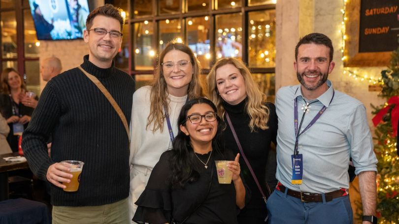Two men and three women pose at a holiday party