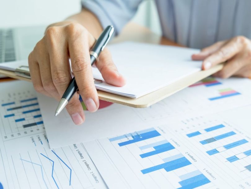Person holding a clipboard and considering financial documents