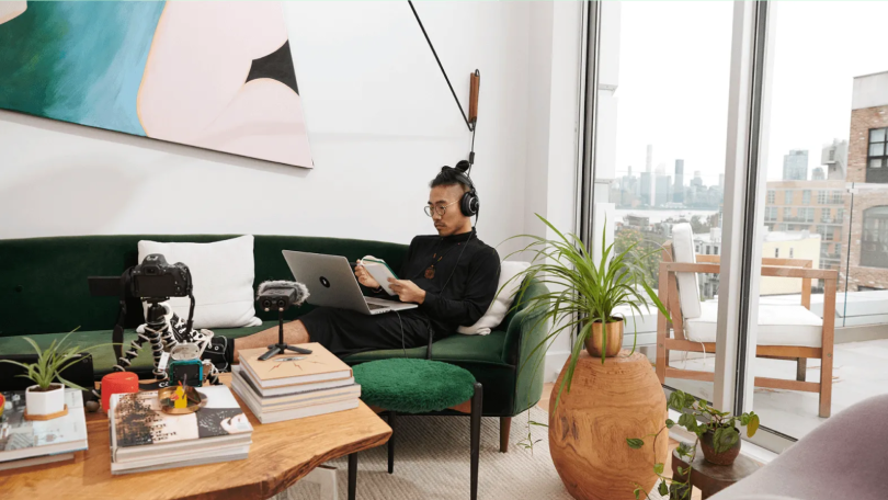 Remote worker sitting on couch with laptop. Nice view in background