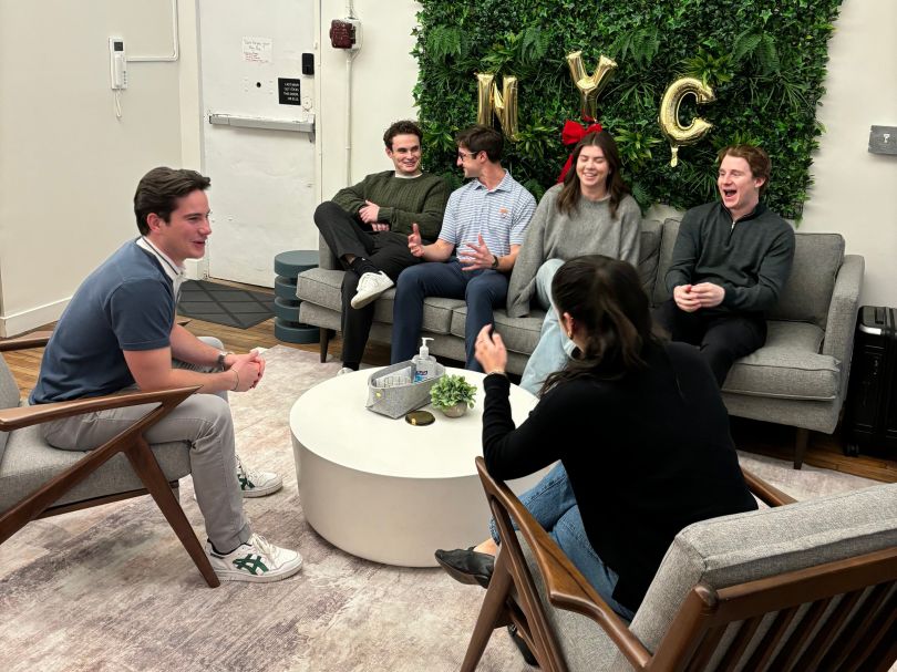 FloQast team members gathered on chairs and couches while chatting in the office.