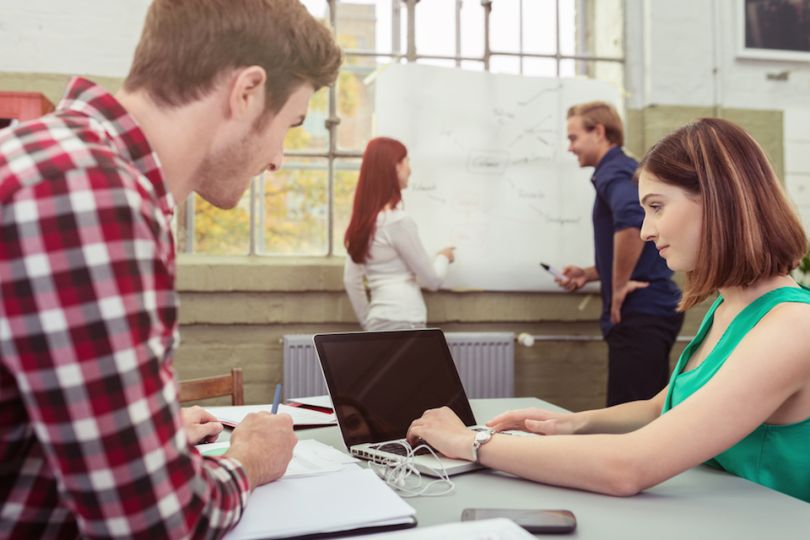 Young professionals work on computer and whiteboard