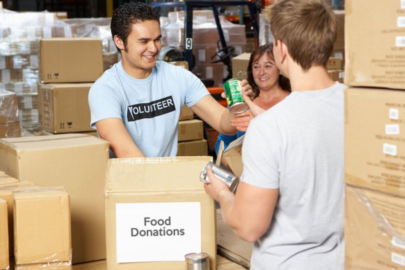 Man volunteers at food bank and gives food to someone