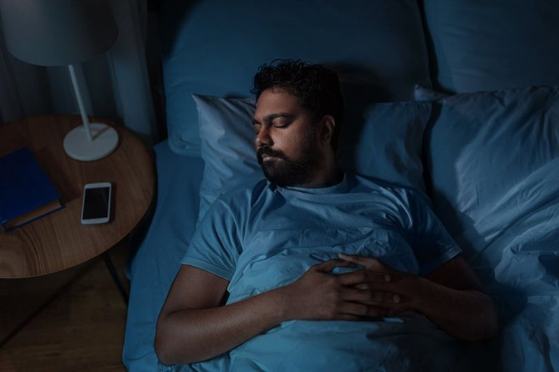 man sleeping in bed at home at night