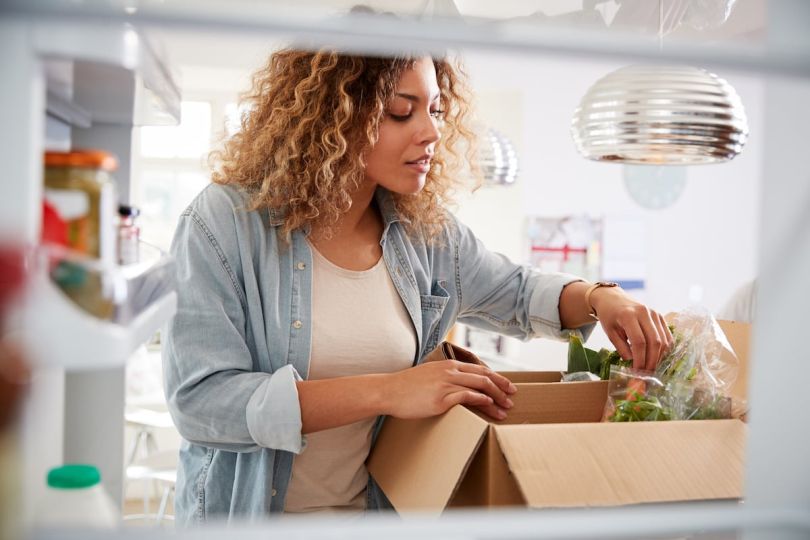 A woman unpacks a box of fresh groceries