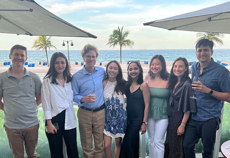 A group of adMarketplace employees pose with beverages on a tropical beach