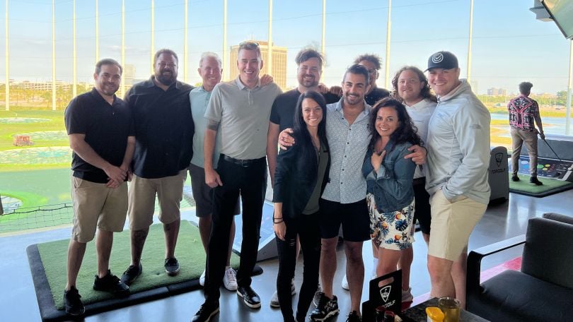 CarAdvise team members pose for a group photo at a driving range. 