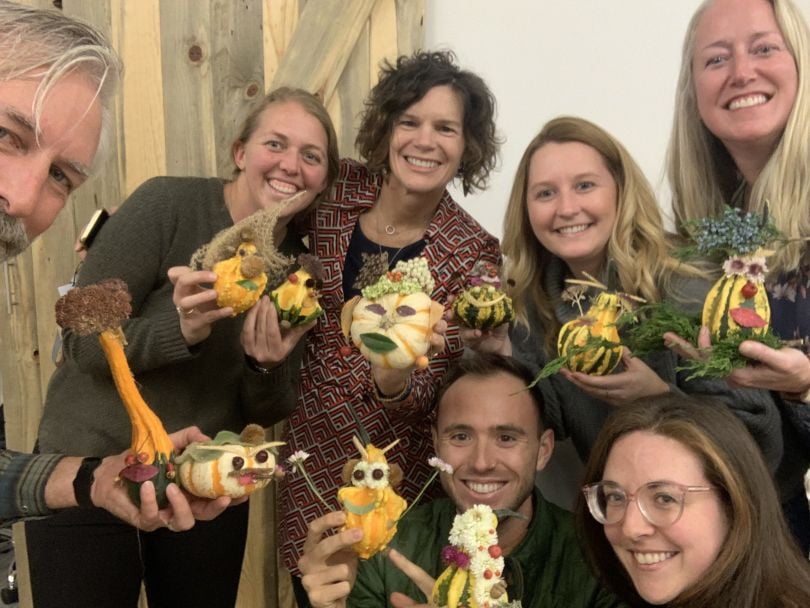 PAIRIN employees holding up small gourds and pumpkins they have decorated to resemble little people.