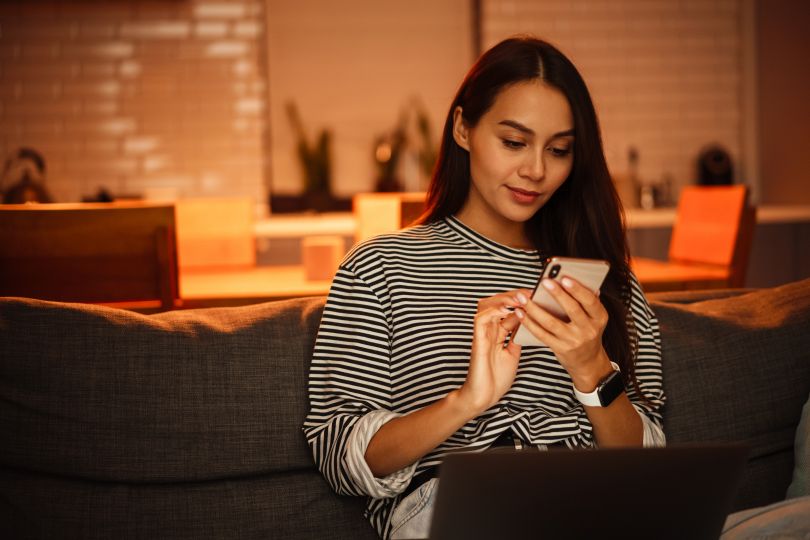 A woman using a phone and laptop