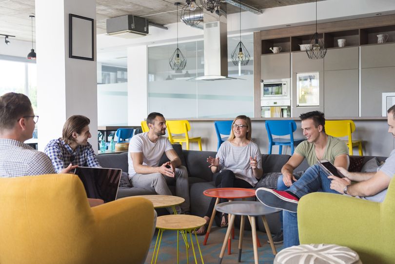 coworkers in a modern office brainstorming while working on laptop and drinking coffee