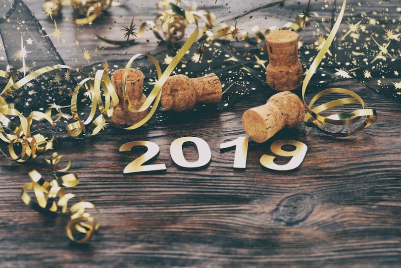 Confetti and glitter beside a gold 2019 placard celebrating the new year