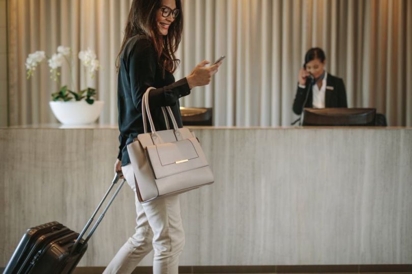 Woman looking at her phone as she walks into hotel
