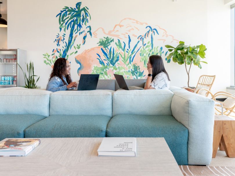 Orchard office with two team members sitting on a couch working on laptops