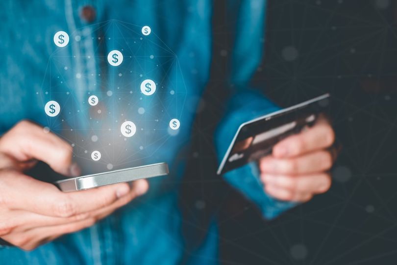 Close up of a man holding a credit card making a purchase on a mobile phone