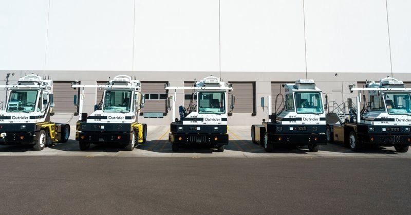 Outrider's autonomous vehicles lined up outside a warehouse.