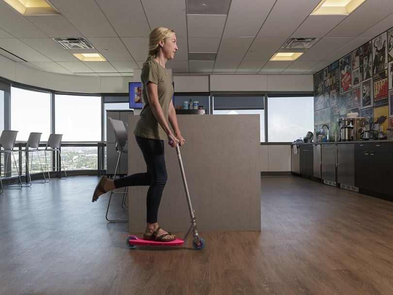 A woman rides a scooter across Pax8's kitchen