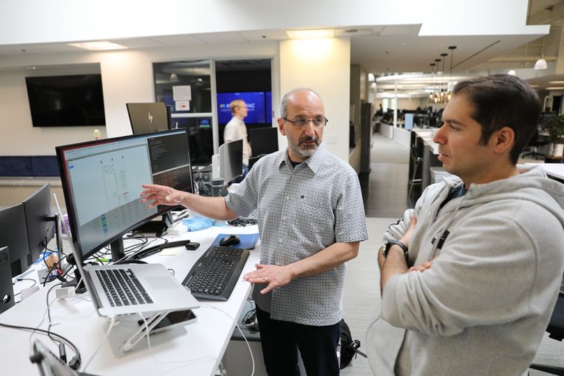 Two Pennymac team members looking at a computer monitor having a discussion