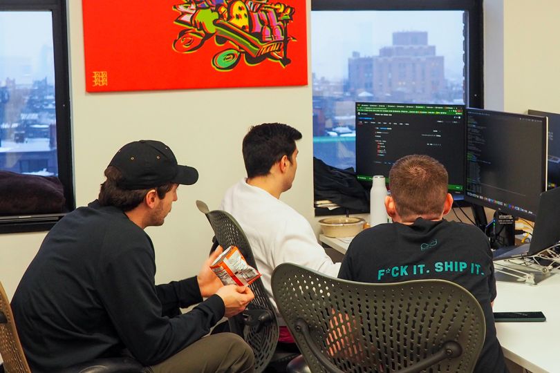 Three RapDev team members gathered around a computer monitor working on a project together