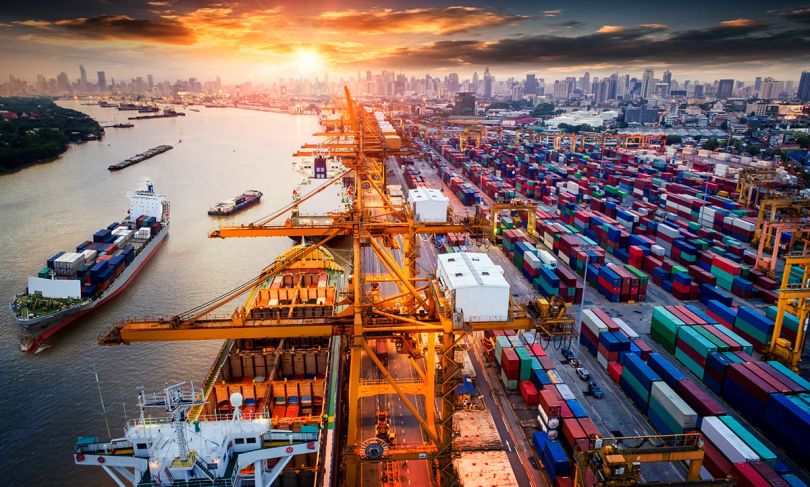 Logistics and transportation of Container Cargo ship and Cargo plane with working crane bridge in shipyard at sunrise